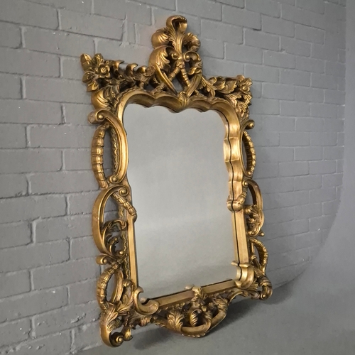 258 - A BAROQUE STYLE RECTANGULAR WALL MIRROR. elaborately moulded and gilded frame, with a large scrollin... 
