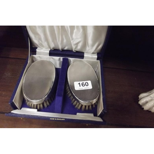 160 - Pair of oval silver backed hair brushes with engine turned decoration, in box.