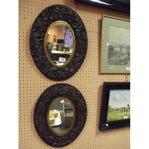 130 - Pair of 19th Century oval wall mirrors in deeply carved pine frames, one dated 1873.