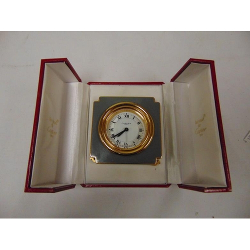 100a - les must de Cartier, gilt brass and enamel cased travelling alarm clock, circular white dial with bl... 