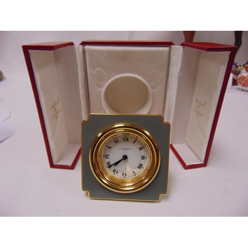 100a - les must de Cartier, gilt brass and enamel cased travelling alarm clock, circular white dial with bl... 