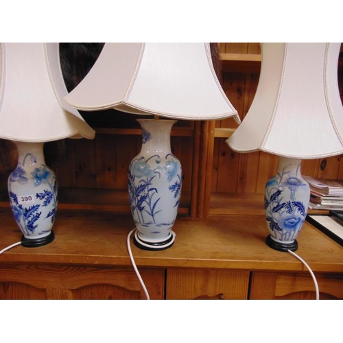 390 - Three blue and white table lamps with shades.