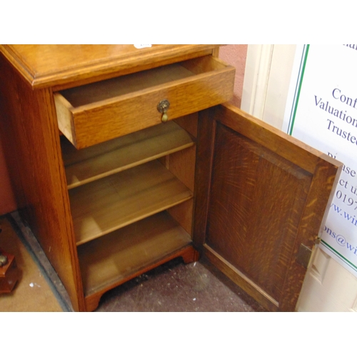 452 - An oak cabinet, dish top, single drawer and cupboard door, on  bracket feet. 33 x 20 x 25