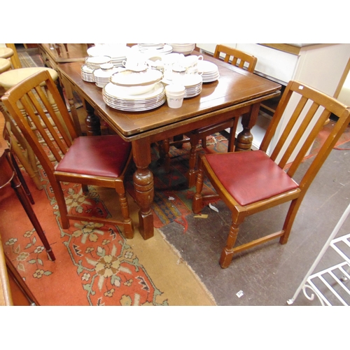 385 - An oak draw leaf table and four chairs.