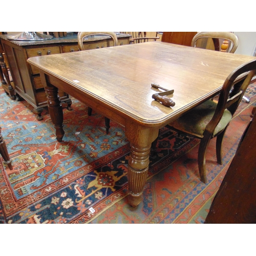 393 - An oak extending dining table, rectangular top, rounded corners and on reeded turned supports with c... 