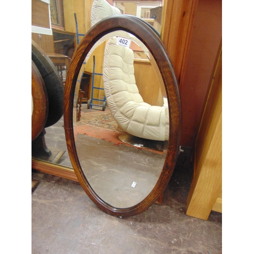 402 - An oak oval bevel edged wall mirror.