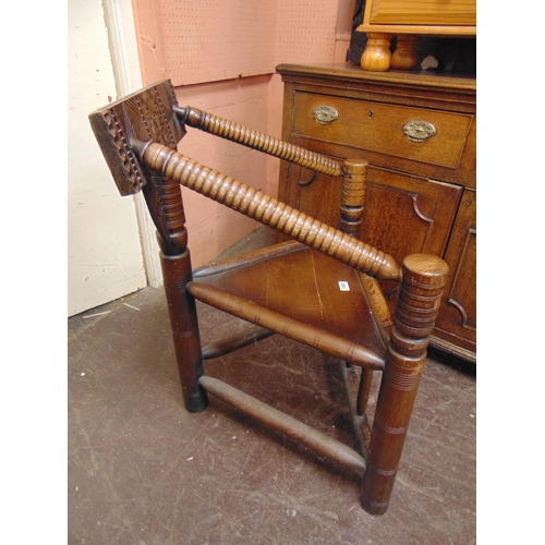 184 - An oak corner  turner's chair, carved decoration, solid seat and on turned supports.