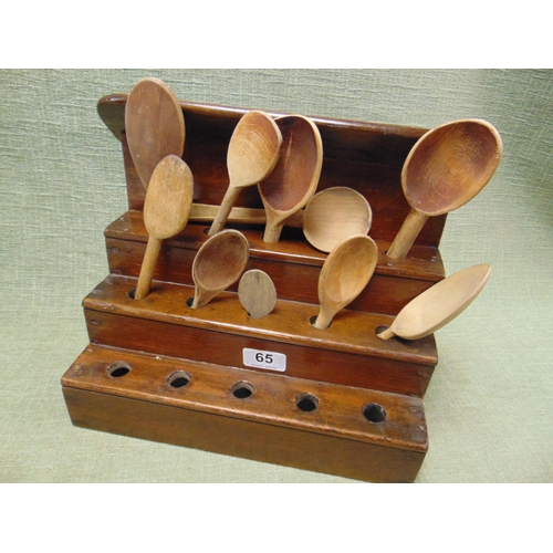 65 - Stepped wooden spoon rack with ten wooden spoons.