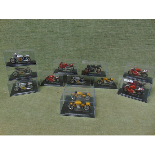 35 - Collection of scale model racing motorbikes in display cases.