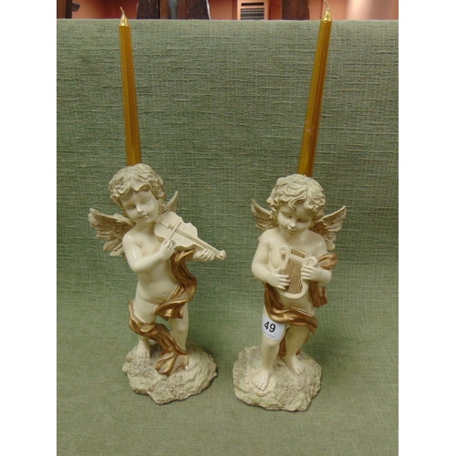 49 - Pair of reproduction cherub form candle holders, each holding a musical instrument. 12