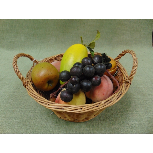 125 - An arrangement of faux fruit, contained in a wicker basket.