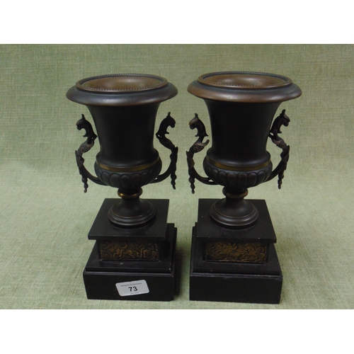 73 - Pair of classical form urns, set on faux slate bases.