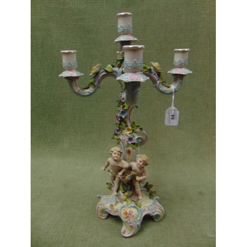 84 - Continental four division floral encrusted candle holder, having cherub form base. 18