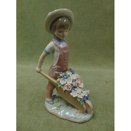 184 - Lladro figure, modelled as a boy pushing a floral wheel barrow.