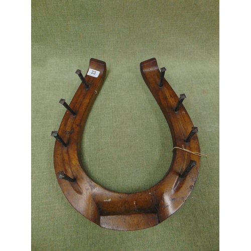 33 - Horseshoe form coat rack.