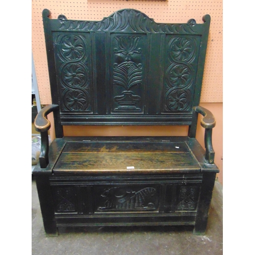 352 - An oak box settle, carved back, open arms, lift up seat and on stile supports. 50 x 38 x 17.5