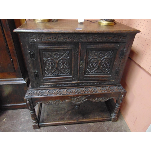 448 - Reproduction oak hutch cupboard on stand, pair of doors and all over carved decoration, on turned su... 