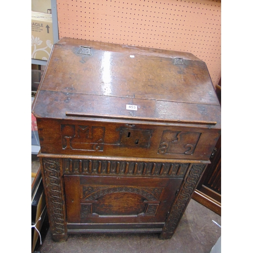 453 - Antique oak desk, having sloping lift up lid, single door with carved and moulded decoration, set on... 