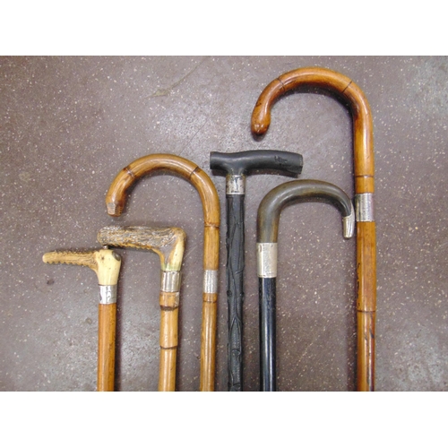 34 - Four silver mounted walking sticks, one other and a riding crop.