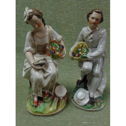 317 - Pair of antique pottery figures, modelled as a man and woman holding baskets of fruit, each 13.5