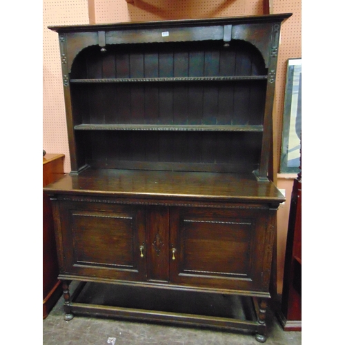 413 - An oak dresser , plate rack back over pair of cupboard doors with brass drop handles  and on platfor... 