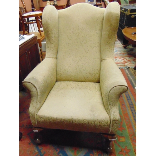 336 - Stout form wingback armchair, set on short turned cabriole supports.