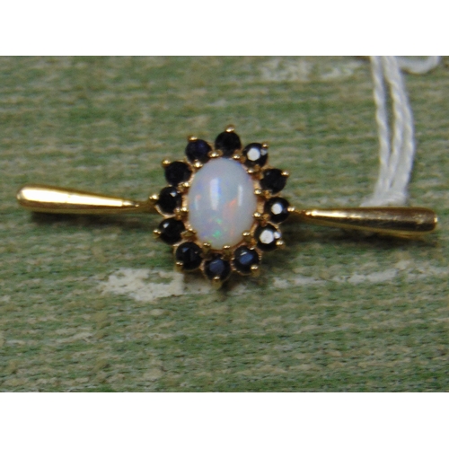 167 - 9ct gold brooch, set with an opal stone surrounded by sapphires.