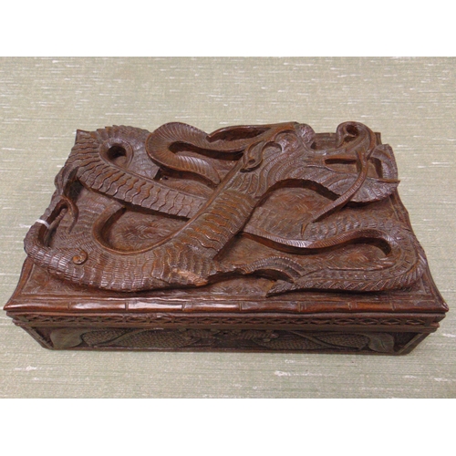 22 - An Oriental lidded box, having carved dragon decoration. 5 x 11 x 6.5