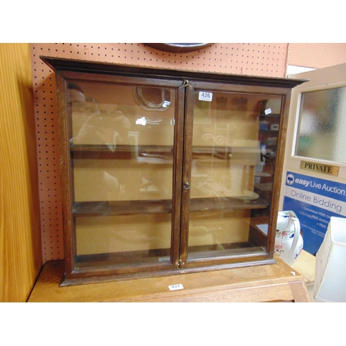 426 - An oak wall cabinet, having ogive cornice and pair of glazed doors. 22 x 26 x 5.5