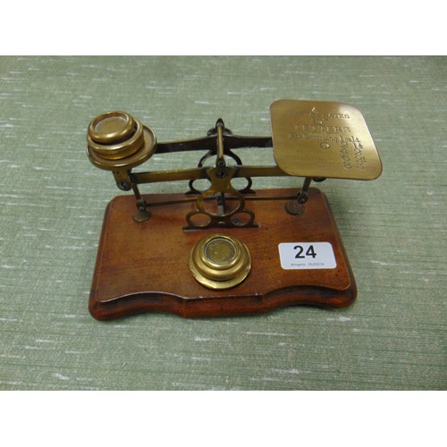 24 - Set of antique brass postal scales and some weights, set on shaped wooden base.