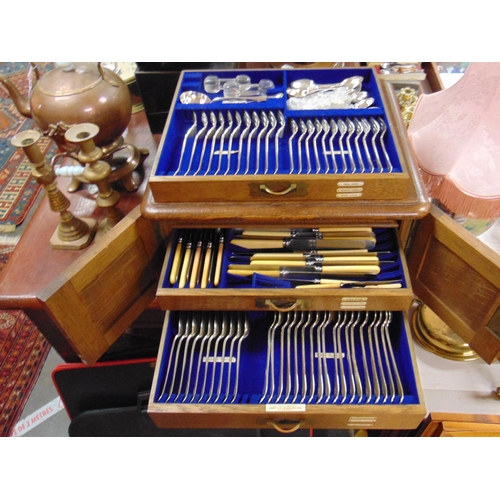 51 - R. Stewart, silver plated canteen of cutlery, contained in an oak three drawer cabinet, having round... 