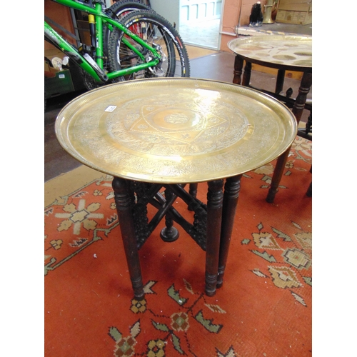 313 - Eastern brass circular topped centre table, set on folding base. 20