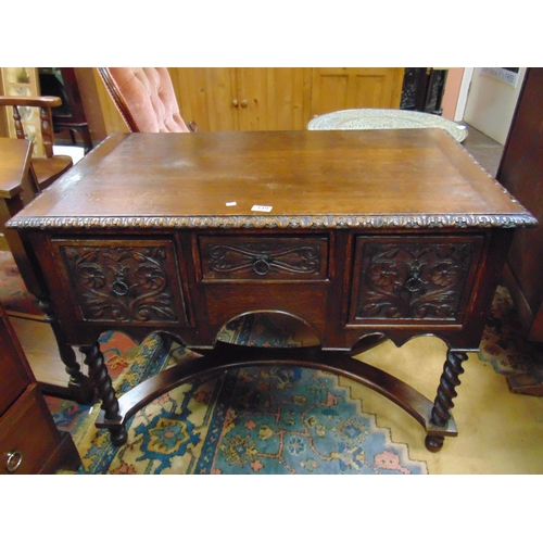 339 - An oak desk, carved frieze, three short drawers with metal handles, on barley twist supports joined ... 