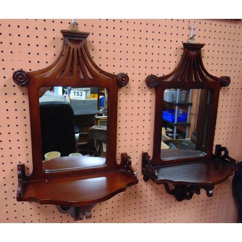 153 - Pair of reproduction mahogany framed wall mirrors, having pierced decoration, and demi lune shelf, e... 