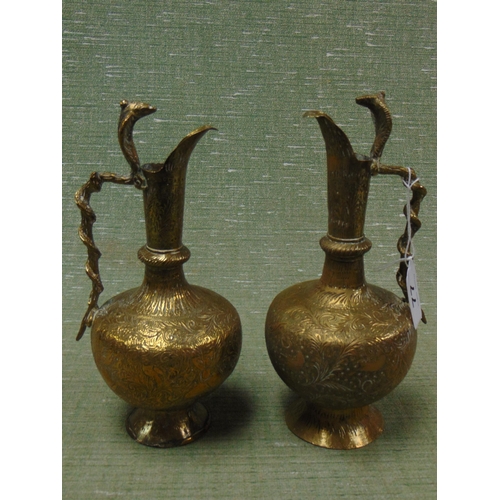 77 - Pair of Eastern brass jugs, having Cobra form handles and engraved decoration, each 9.5