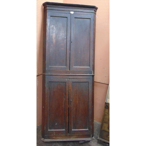 333 - An antique freestanding oak corner cupboard, having four panel doors, enclosing a shelf lined interi... 