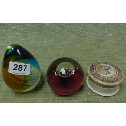 287 - Two coloured glass paperweights and a cherry toothpaste jar.