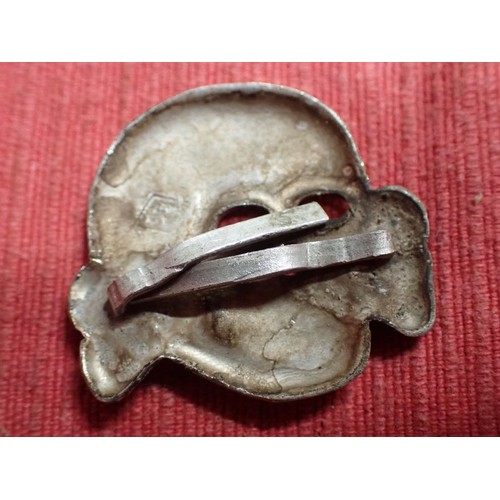 52 - WW2 German SS visor cap death's head badge

Die-stamped aluminium totenkopf. Untouched with a light ... 