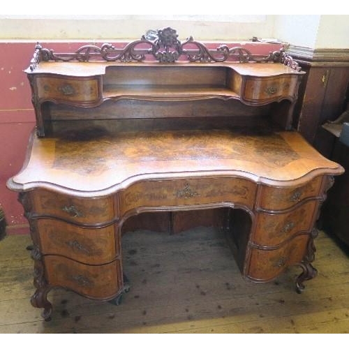 10 - A burr walnut writing desk, having cross banded serpentine shaped front, with galleried shelf and dr... 