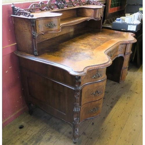 10 - A burr walnut writing desk, having cross banded serpentine shaped front, with galleried shelf and dr... 