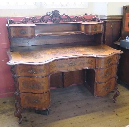 10 - A burr walnut writing desk, having cross banded serpentine shaped front, with galleried shelf and dr... 