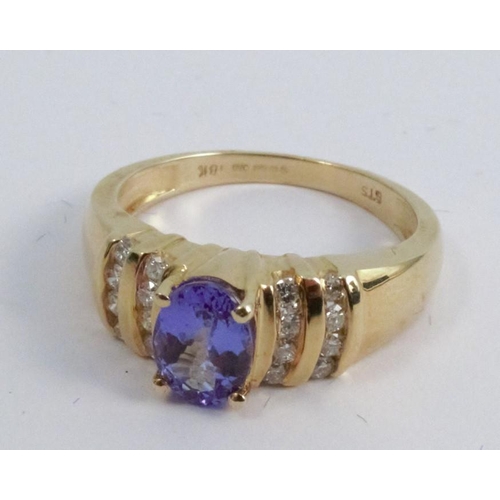 259 - A tanzanite and diamond 18 carat gold ring, the oval cut stone with channel set brilliants to each s... 