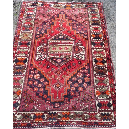 52 - An Eastern style rug, the red ground decorated with repeating symbols, 55ins x 80ins