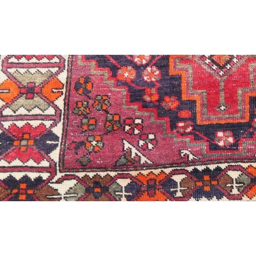 52 - An Eastern style rug, the red ground decorated with repeating symbols, 55ins x 80ins