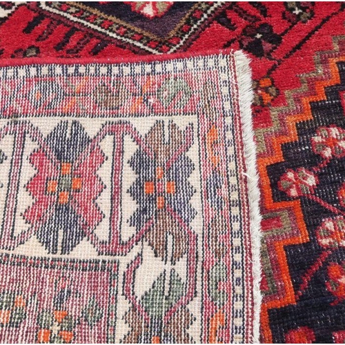 52 - An Eastern style rug, the red ground decorated with repeating symbols, 55ins x 80ins