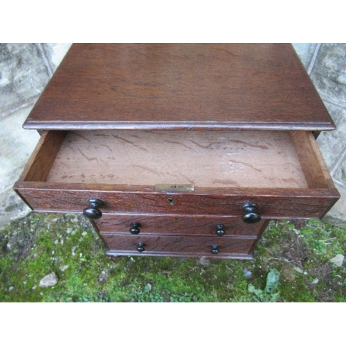 28 - A 19th century late Georgian oak miniature chest of drawers, having five graduated drawers with ebon... 