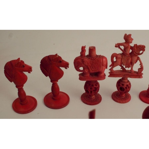 153 - A collection of carved bone chess pieces, some carved with puzzle balls, natural or stained red, in ... 