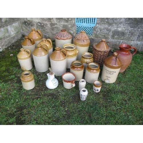 65 - A large collection of stoneware bottles, some with wicker mounts and a jug