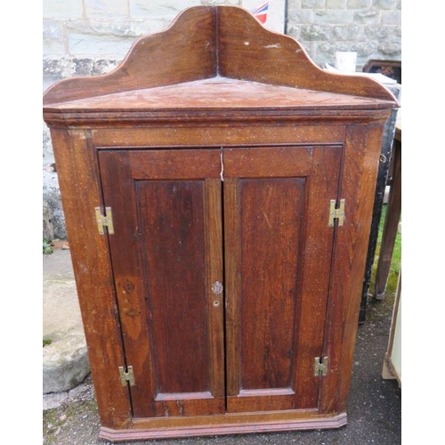 70 - An oak corner cabinet, with a pair of fielded doors opening to reveal three shaped painted shelves