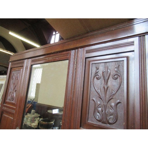 73 - An Edwardian mirror door wardrobe, with carved decoration and drawers to the base, width 49ins, heig... 